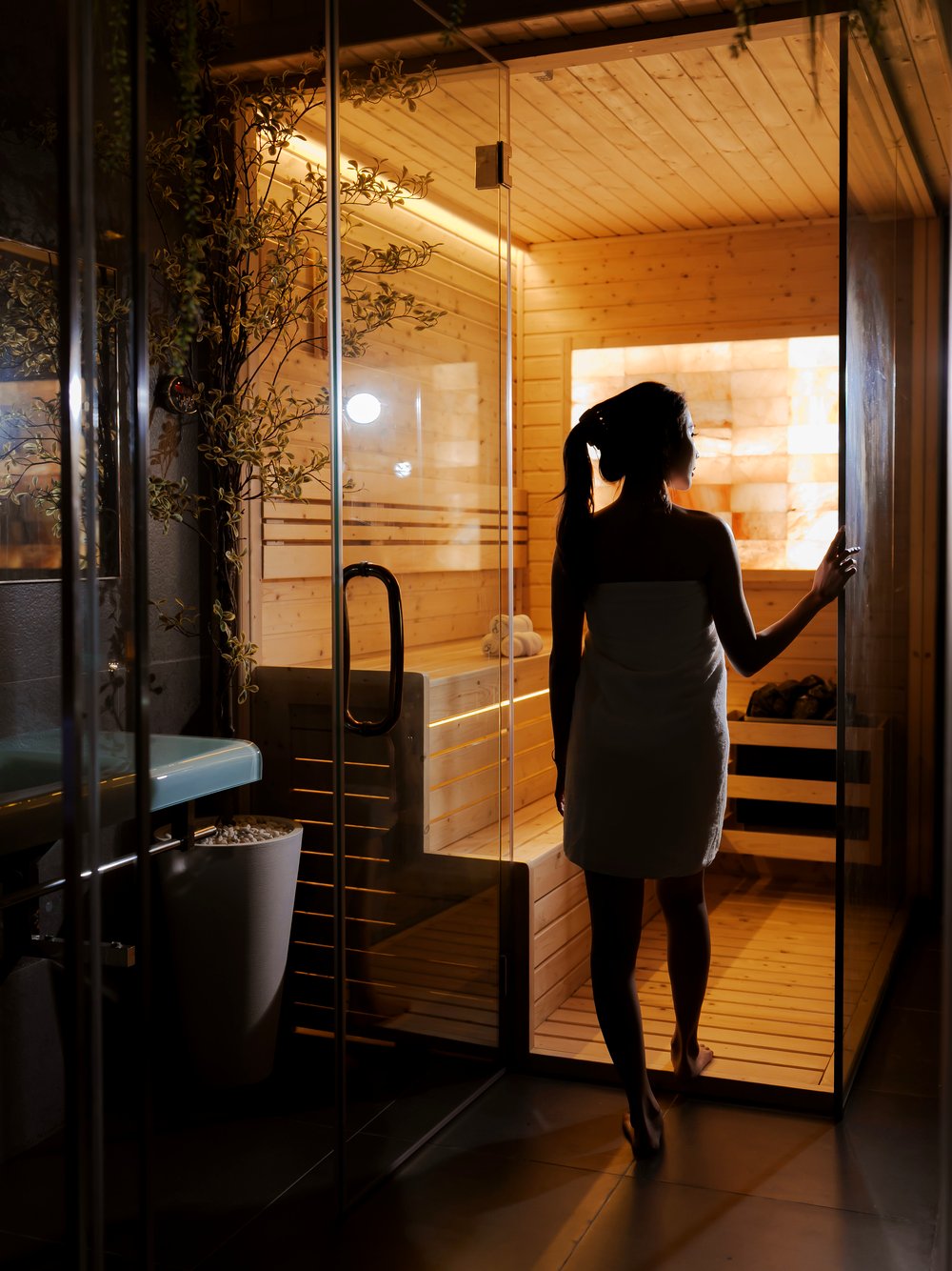 Guest stepping into the Himalayan salt-wall sauna, silhouetted in the evening light