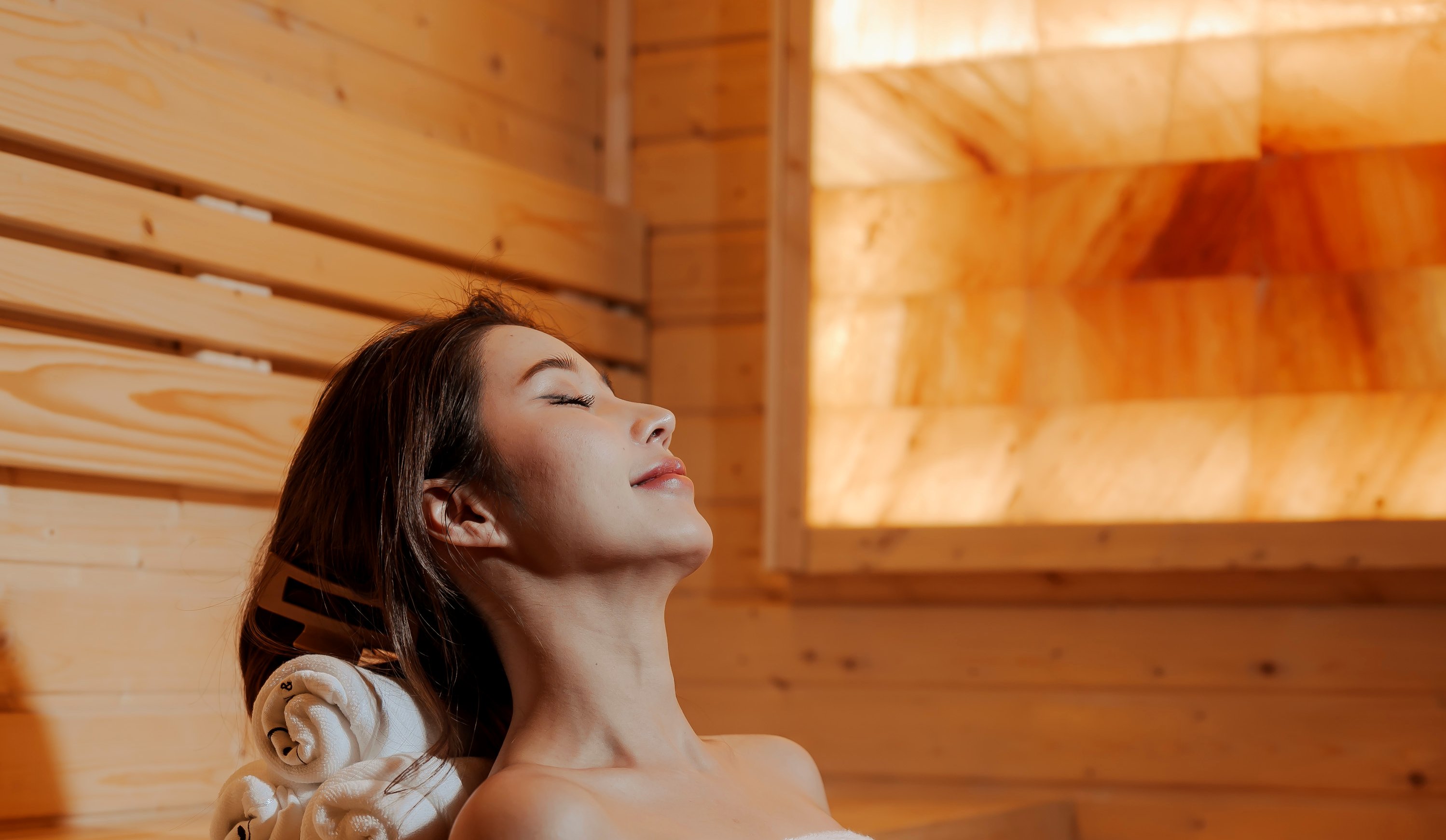 Guest relaxing against the glowing Himalayan salt wall inside the private sauna